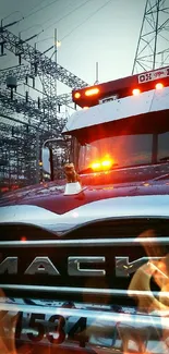 Mack truck in industrial landscape with electrical towers.