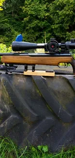 Rifle with scope on forest tire backdrop