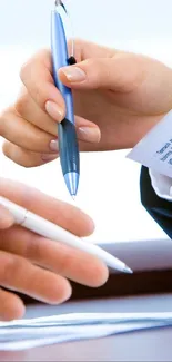 Hands exchanging pens in a business setting.