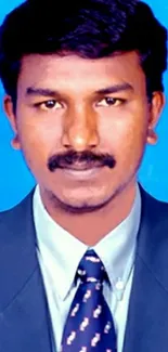 Professional portrait with blue background in formal attire.