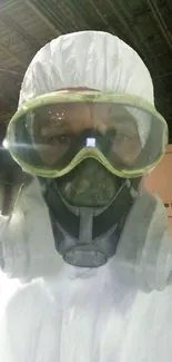 Person wearing full protective gear with mask and goggles in industrial setting.