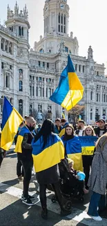 Crowd waving blue and yellow flags during a city protest.