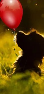 Puppy in a field looking at a red balloon.