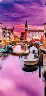 Venetian canal at sunset with purple sky and boats.