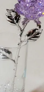 Purple crystal rose in a glass vase with shimmering leaves.