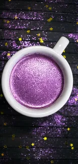 Glittery purple coffee cup with stars on dark wood.