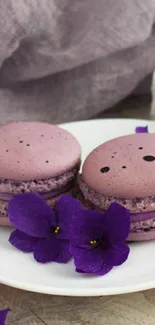 Purple macarons with violet flowers on a plate.