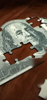 Puzzle piece of hundred dollar bill on wooden background.