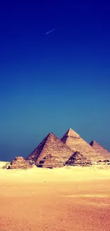 Majestic pyramids under a vibrant blue sky with desert sands.