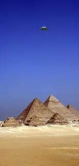 UFO hovering over pyramids in a blue sky.