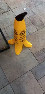 Quirky banana-shaped caution sign on urban tile floor.