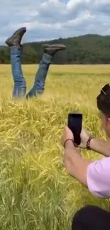 Man photographing legs in a wheat field.