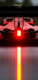 Rear view of a racing car with glowing red lights on a wet track.