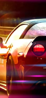 Red sports car driving into the sunset on an open highway.