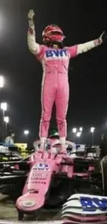 Race car driver celebrates victory at night on vehicle.