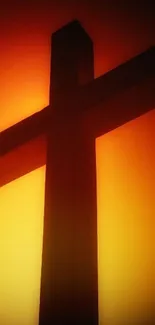 Silhouette of cross against a glowing orange sky.