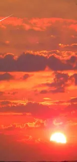 Vibrant red sunset with clouds and meteor across the sky.