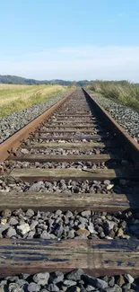 Railroad tracks under a clear blue sky extend into the distance.