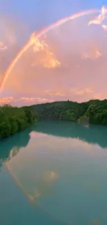 Majestic rainbow over peaceful river with lush green trees and sunset sky.