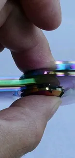 Close-up of a spinning rainbow fidget spinner held between fingers.