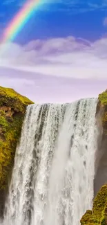 Waterfall cascading with a rainbow overhead under a blue sky.