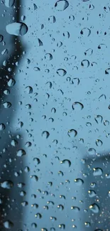 Raindrops on a glass surface with a blue background in a mobile wallpaper.