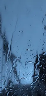 Raindrops on a glass surface with a blue background, creating a serene effect.