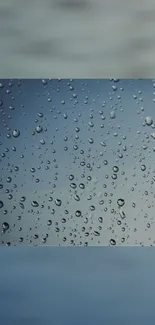 Raindrops on windowpane with blue gradient background.