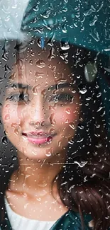 Woman behind raindrop covered glass, holding an umbrella.