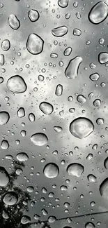 Close-up of raindrops on a window with a cloudy gray background.