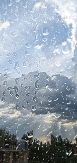 Raindrops on glass with cloudy sky background.