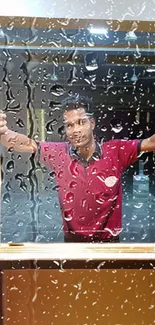 Mobile wallpaper with raindrops on a window and a person in a maroon shirt.