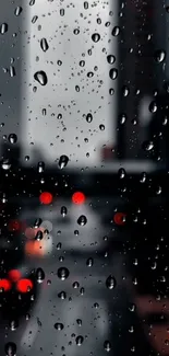 Raindrops on a window with a blurred cityscape background at night.