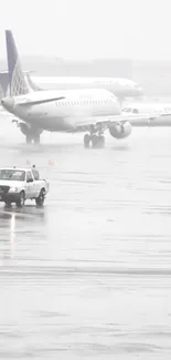 Gray-toned rainy airport tarmac with planes and vehicle.