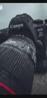 A close-up view of a Canon camera with raindrops on the lens.