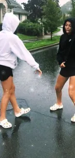 Two friends joyfully dancing on a rainy street.