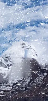 Mountain view with raindrops on glass, blue sky visible.