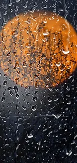 Orange moon behind raindrop-streaked glass on a nighttime background.