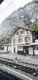 Train station view with raindrops on a window and mountains in the background.