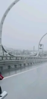 Rainy highway with motorcycle on bridge.
