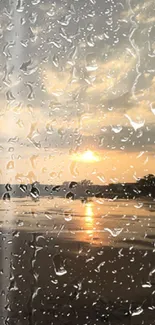 Rainy sunset beach view with raindrops on windowpane.