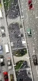 Raindrops on a window overlooking a city street with cars.