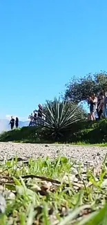 Rally car on a dirt road under a bright blue sky with spectators.