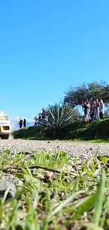 Rally car speeding on a countryside dirt road with lush greenery and clear blue skies.