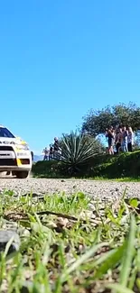 Rally car racing in natural landscape under blue sky.