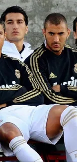 Real Madrid players in black jerseys on the bench, focused and ready.