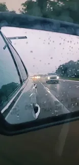 Rainy road seen through a car's rearview mirror, reflecting vehicles in motion.