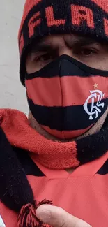 Fan dressed in red and black with a cap and scarf.