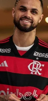 Man in red and black sports jersey smiling in vibrant background.