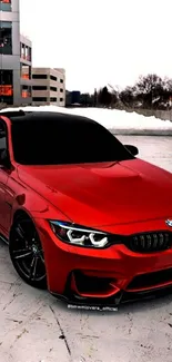 Red BMW sports car parked in urban setting on snowy day.